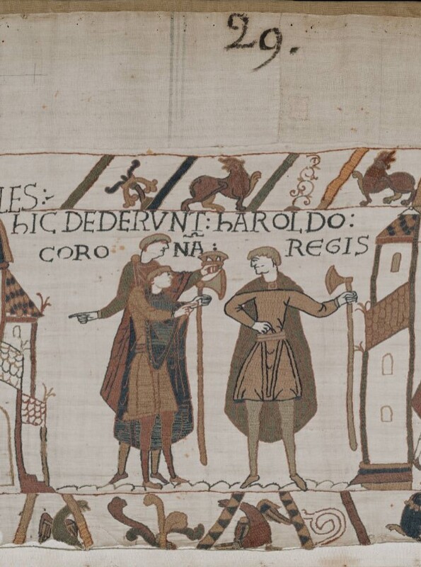 A screenshot of panel 29 of the Bayeux Tapestry. Three figures with dane axes converse.