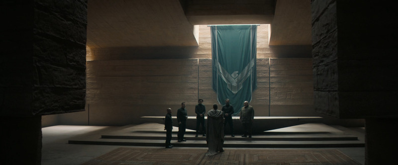 Dark room serving as the Atreides command center. Figures of high status stand and a large Atreides banner decorates the wall.