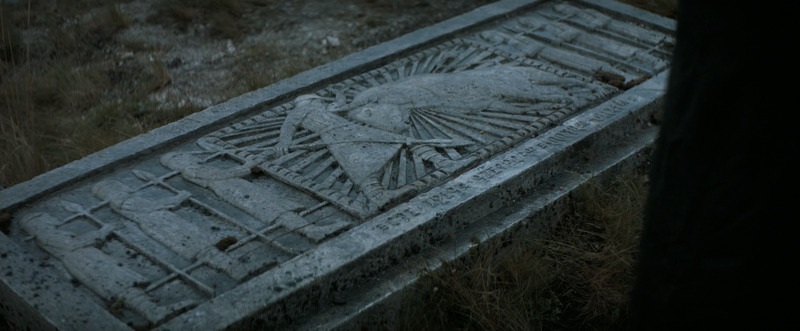 Still shot from Dune (2021). Overhead shot of the grandfather’s tomb. Tomb decorated with figures sculpted in relief depicting the entombed battling with a bull while surrounded by other human figures.