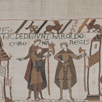 A screenshot of panel 29 of the Bayeux Tapestry. Three figures with dane axes converse.