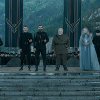 Duke Leto Atreides stands with his military and council. All dressed in military attire standing tall. 
Banners appear in the background with the Atreides symbol. Outdoors, separated from the lush environment by a stone platform.
